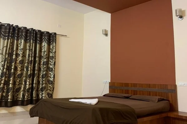 Standard double room with wooden bed and curtained window at Narasinha Mehta Dham